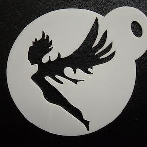 May include: A circular white stencil featuring a die-cut silhouette of a winged figure in flight. The design shows a stylised person with long hair and large, sweeping wings extending upwards. A small circular hole is positioned at the top right edge.
