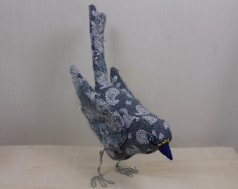 Small decorative bird in grey and white fabric.