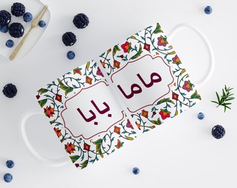 May include: White ceramic mug with a floral pattern in shades of red, orange, green, and blue. The words "Baba" and "Mama" are written in a burgundy font on the mug.