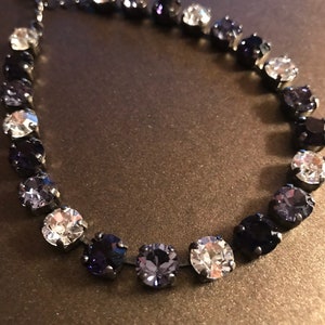May include: A black chain necklace with a gradient of clear, light blue, and dark blue round crystals.