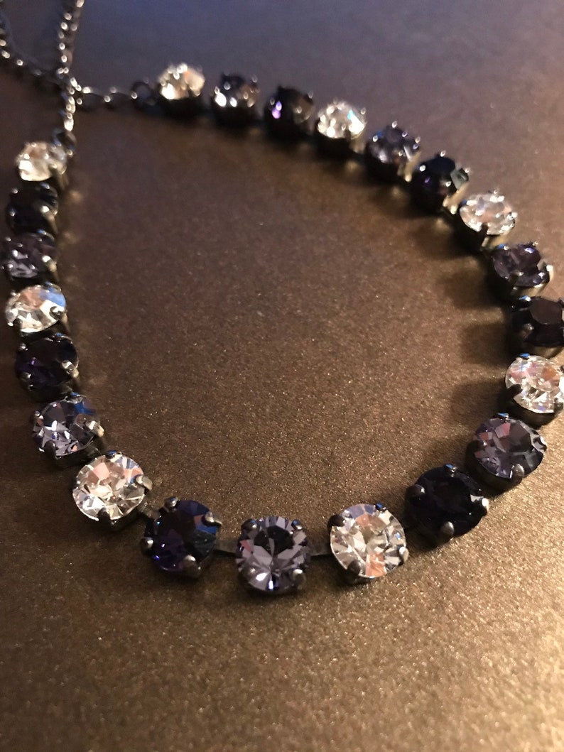 May include: A black chain necklace with a gradient of clear, light blue, and dark blue round crystals.