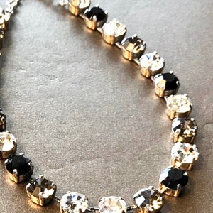 Collar de plata con diamantes negros, detalles plateados, cristales Swarovski negros y transparentes de brillo clásico. Cadena tipo copa, pendientes con cierre de palanca. imagen 2