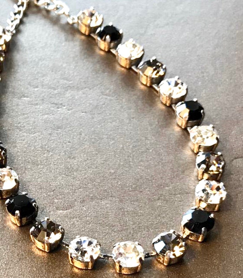 Collar de plata con diamantes negros, detalles plateados, cristales Swarovski negros y transparentes de brillo clásico. Cadena tipo copa, pendientes con cierre de palanca. imagen 2