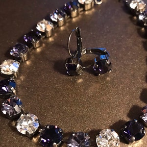 May include: A silver necklace and earrings set with a gradient of clear and dark purple crystals.