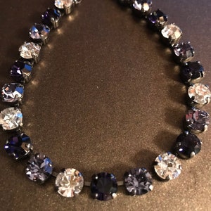 May include: A silver chain bracelet with a gradient of clear, light purple, and dark purple round crystals.
