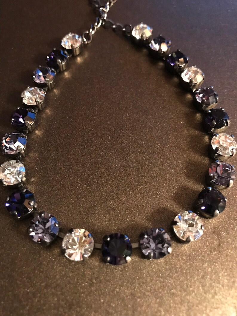 May include: A silver chain bracelet with a gradient of clear, light purple, and dark purple round crystals.