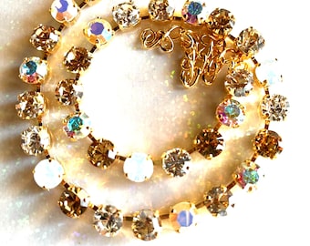 May include: A gold chain bracelet with clear and iridescent crystals. The bracelet has a lobster clasp closure.