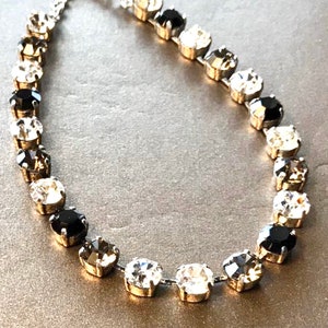 Puede incluir: Un collar de cadena de plata con piedras de cristal negras y transparentes. Las piedras est&aacute;n dispuestas en un patr&oacute;n de degradado, comenzando con negro en un lado y pasando a transparente en el otro.