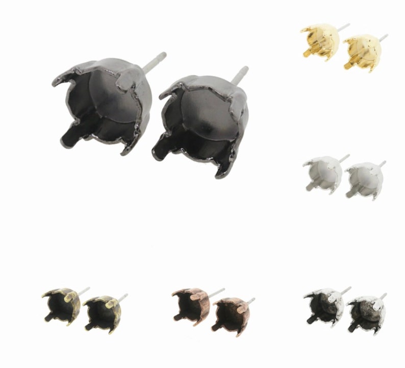 May include: A set of six pairs of earring settings in various finishes, including black, silver, gold, and antique bronze. Each setting features a round bezel with a pronged edge, designed to hold a round stone or cabochon.