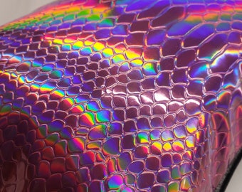 May include: A close-up of a pink iridescent snakeskin-textured pouch with a black trim.