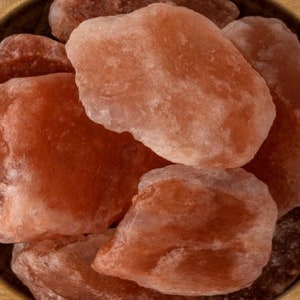 May include: Close-up of a bowl filled with large, rough, pink Himalayan salt crystals.