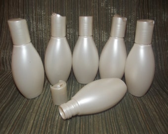 May include: Seven white plastic bottles with silver caps. The bottles are oval shaped and have a pearlescent finish.