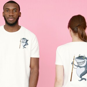 May include: White t-shirt featuring a cartoon shark holding a pool cue. The shark is grey with a white belly and has a toothy grin. The t-shirt is shown in both front and back views.