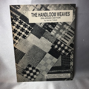 May include: A black and white book cover with the title "The Handloom Weaves Enlarged Edition" by Harriet Tidball. The cover features a collage of different woven fabric patterns. The book is a publication of the Shuttle Craft Guild, Monograph Thirty-Three.