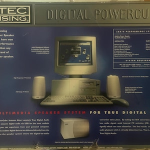 May include: A black and blue box with the text "Altec Lansing Digital PowerCube" on the front. The box shows a computer with a monitor and speakers. The text "The Multimedia Speaker System for True Digital Audio" is at the bottom of the box.