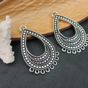 May include: Two silver teardrop-shaped earring charms with a beaded design and a loop at the top for attaching to jewellery.