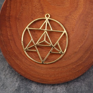 Puede incluir: Un colgante de metal dorado en forma de círculo con un diseño de estrella geométrica en su interior.
