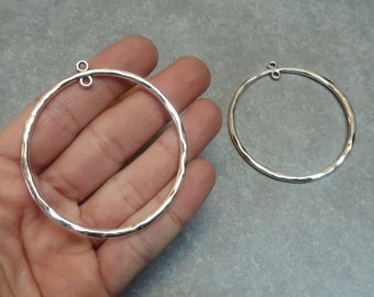 Puede incluir: Dos pendientes de aro martillados de plata con un aro de salto en la parte superior para sujetarlos a una cadena u otras joyas.