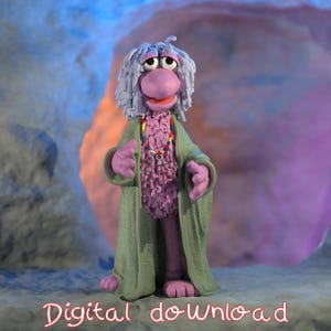 May include: A purple puppet with long white hair wearing a green robe and a colorful beaded necklace. The puppet is standing in front of a cave-like background.