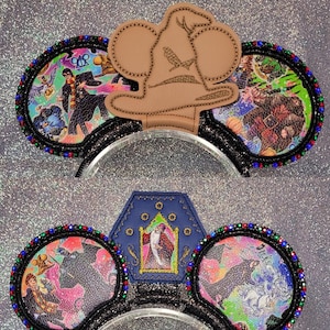 Puede incluir: Un par de orejas de ratón negras con un sombrero de fieltro marrón con punta y una casa de fieltro azul con ribetes dorados y una figura en el interior. Las orejas están decoradas con brillantes de colores e imágenes de la serie Harry Potter.