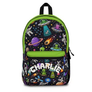 May include: A black backpack with bright green trim featuring a space-themed pattern of astronauts, planets, stars, and flying saucers with aliens. The front pocket displays the name CHARLIE in large, bold, white, rounded capital letters.