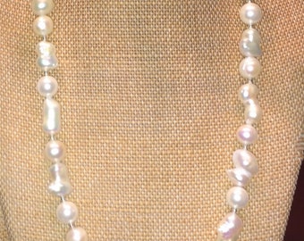 May include: A white pearl necklace with a silver clasp. The pearls are irregular in shape and size, giving the necklace a unique and elegant look.