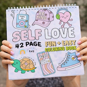 May include: A spiral-bound coloring book with the words "SELF LOVE" in large letters. The cover features whimsical illustrations of a music player, a baseball cap, a heart with headphones, a turtle, a phone, and a sneaker. The text reads "42 PAGE FUN + EASY COLORING BOOK".