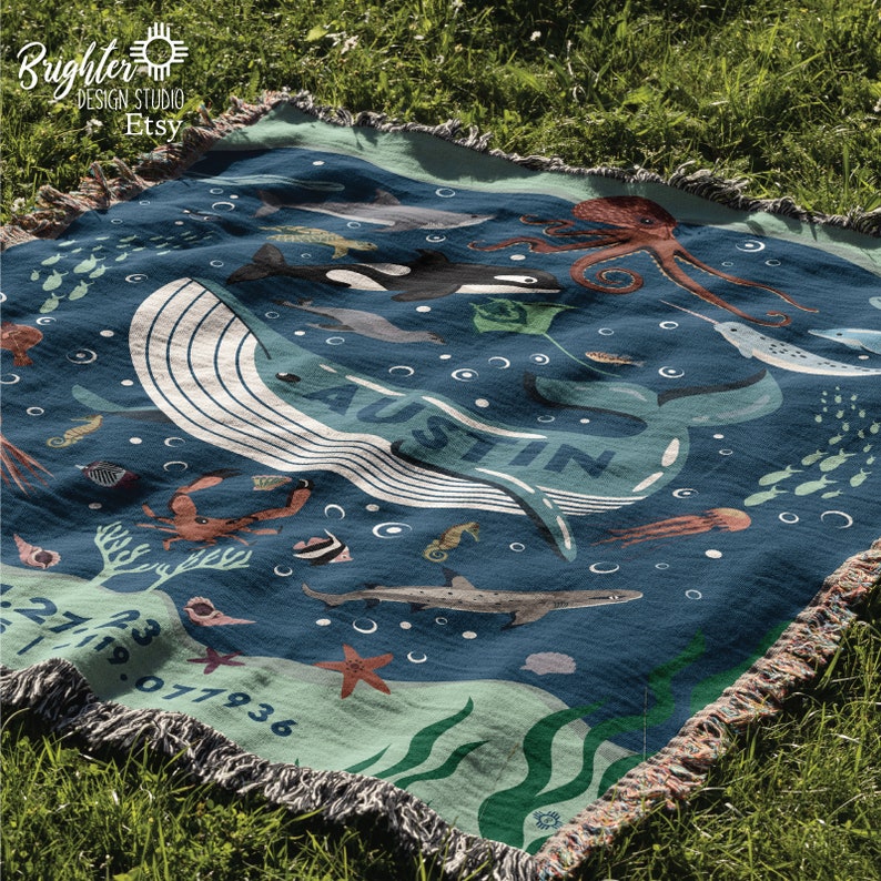 May include: A blue and green woven blanket with a whale, octopus, and other sea creatures. The blanket has the name "Austin" written on it.