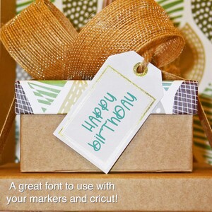 K&ouml;nnte beinhalten: Eine kleine Geschenkbox mit einem wei&szlig;en Anh&auml;nger mit der Aufschrift "Happy Birthday" in t&uuml;rkisfarbener Schrift. Der Anh&auml;nger hat einen goldenen Rand und ist mit einer goldenen Schnur gebunden. Die Box ist mit einem goldenen Band verpackt.