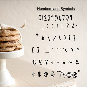K&ouml;nnte beinhalten: Ein Stapel Schokoladen-Chip-Cookies, mit einem wei&szlig;en Band gebunden, steht auf einem wei&szlig;en Sockel. Das Bild zeigt auch eine Liste von Zahlen und Symbolen, einschlie&szlig;lich Satzzeichen und W&auml;hrungssymbolen.