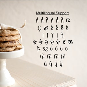 K&ouml;nnte beinhalten: Ein Stapel Schokoladen-Chip-Cookies, gebunden mit einem wei&szlig;en Band, steht auf einem wei&szlig;en Kuchenst&auml;nder. Der Text "Multilingual Support" steht &uuml;ber einer Liste schwarzer Sonderzeichen.