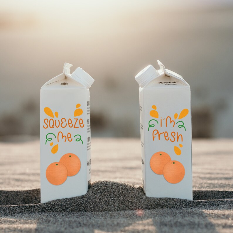 K&ouml;nnte beinhalten: Zwei wei&szlig;e Saftkartons mit orangefarbenen und gr&uuml;nen Grafiken und den S&auml;tzen "squeeze me" und "I'm fresh". Jeder Karton zeigt ein Paar Orangenillustrationen. Die Kartons stehen auf einer sandigen Oberfl&auml;che.