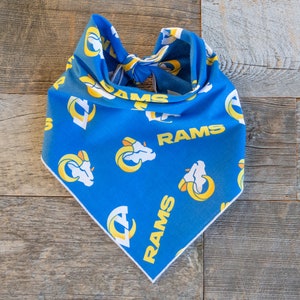 May include: Blue bandana with a yellow and white Rams logo pattern. The bandana has a knotted tie at the top.