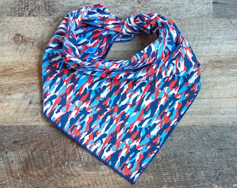 May include: A red, white, and blue bandana with a camouflage pattern. The bandana is folded in half and tied in a knot.