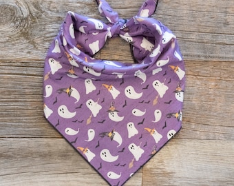May include: Purple bandana with a pattern of white ghosts and orange witch hats. The bandana is tied in a knot at the top.
