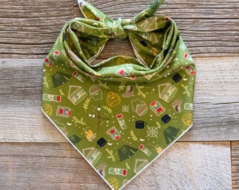 May include: Green bandana with a white border featuring a camping themed pattern with illustrations of tents, campfires, lanterns, and other camping gear.