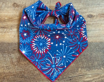 May include: A blue bandana with a red, white, and blue firework pattern. The bandana is tied in a knot at the top.