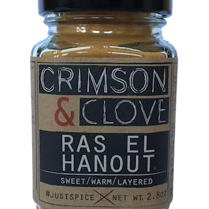 May include: A glass jar with a black lid filled with a spice blend. The label is brown with black text that reads "CRIMSON & CLOVE RAS EL HANOUT. SWEET/WARM/LAYERED #JUSTSPICE NET WT. 2.80Z"
