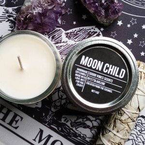 Peut inclure: Un bocal de bougie noir et argent avec l'&eacute;tiquette "MOON CHILD" et le texte "HANDMADE | GOOD VIBES SCENT | SOY CANDLE | MADE WITH LOVE JUST FOR YOU | CREATED FROM THE COSMOS | NET 4 OZ".