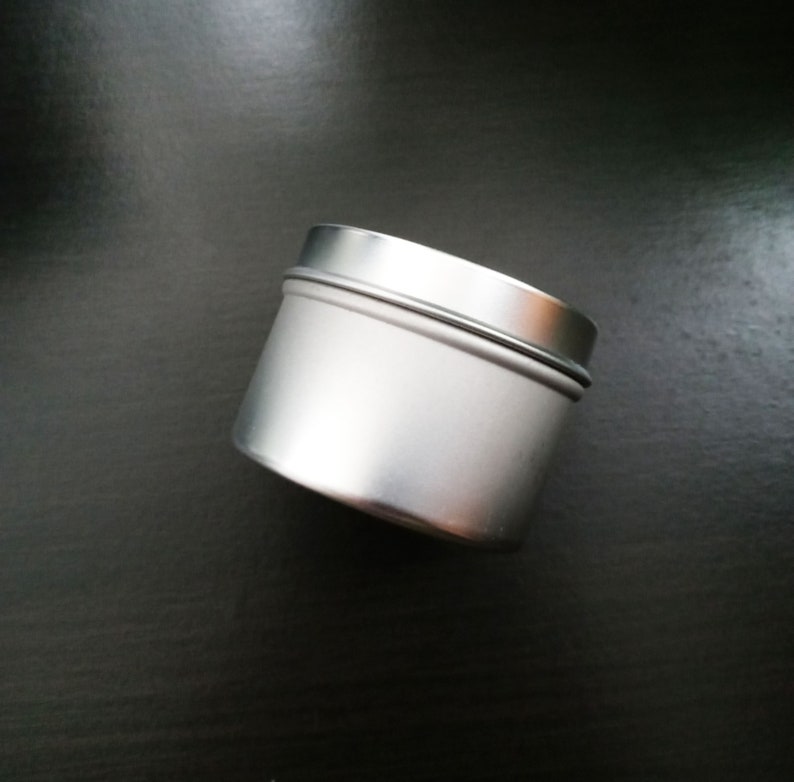 Peut inclure: Un r&eacute;cipient en m&eacute;tal argent&eacute; avec une surface lisse et arrondie. Le r&eacute;cipient a un couvercle et est vide.