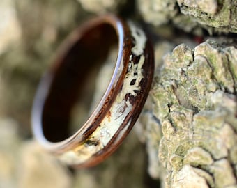 May include: A wooden ring with a white inlay design. The ring is brown and has a natural wood grain.