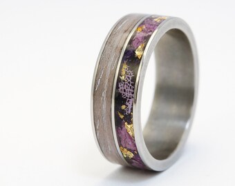 May include: A silver ring with a band of wood and purple and gold inlay.