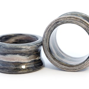 May include: Two wooden ear gauges, one with a light brown and gray wood grain pattern and the other with a darker brown and gray wood grain pattern.