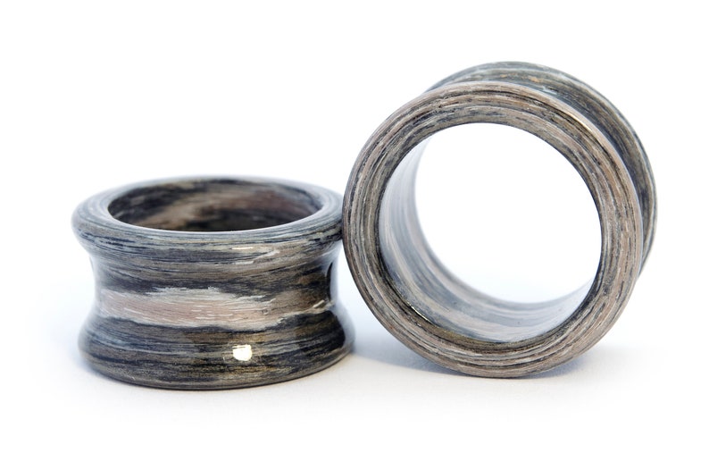 May include: Two wooden ear gauges, one with a light brown and gray wood grain pattern and the other with a darker brown and gray wood grain pattern.
