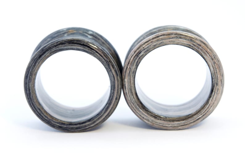 May include: A pair of wooden ear gauges with a black and white wood grain pattern. The gauges are round and have a smooth, polished finish.