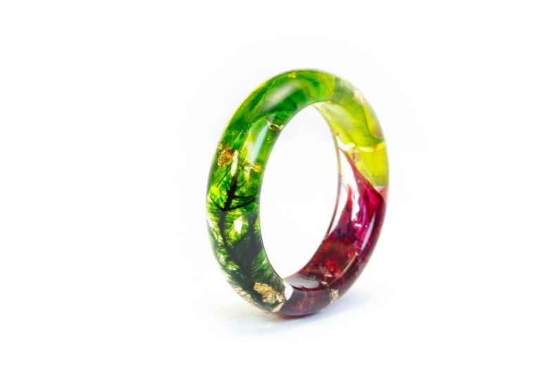 May include: A colorful resin ring with a nature-inspired design. The ring features a gradient of green, yellow, and red hues, with gold leaf accents. The ring is a unique piece of jewelry.
