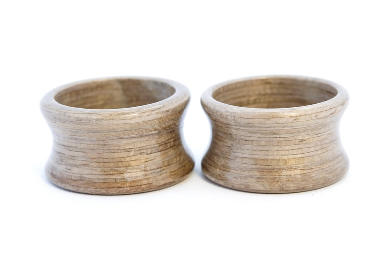 May include: Two wooden rings with a light brown color and a wood grain pattern. The rings are slightly flared at the top and bottom.