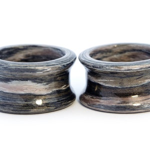 May include: Two gray and brown striped wooden rings. The rings are smooth and have a glossy finish.