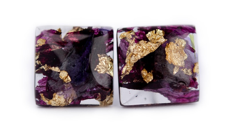 May include: A pair of square resin earrings with purple and gold flower petals and gold leaf accents.