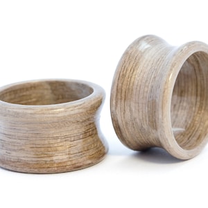 May include: Two wooden rings with a light brown finish. The rings are made of thin layers of wood that are glued together. The rings are smooth and polished.